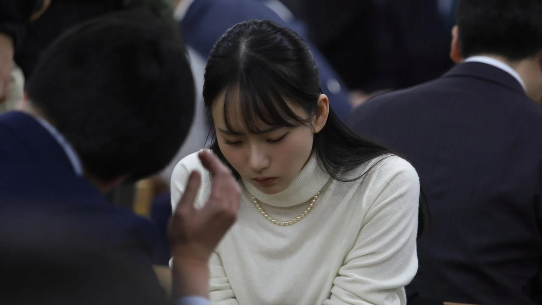 大勢の観戦者に囲まれた会場で、碁盤に向かって対局する三島響